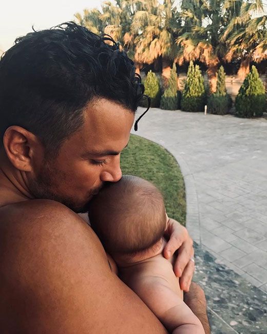 Shirtless Peter Andre holding a newborn baby