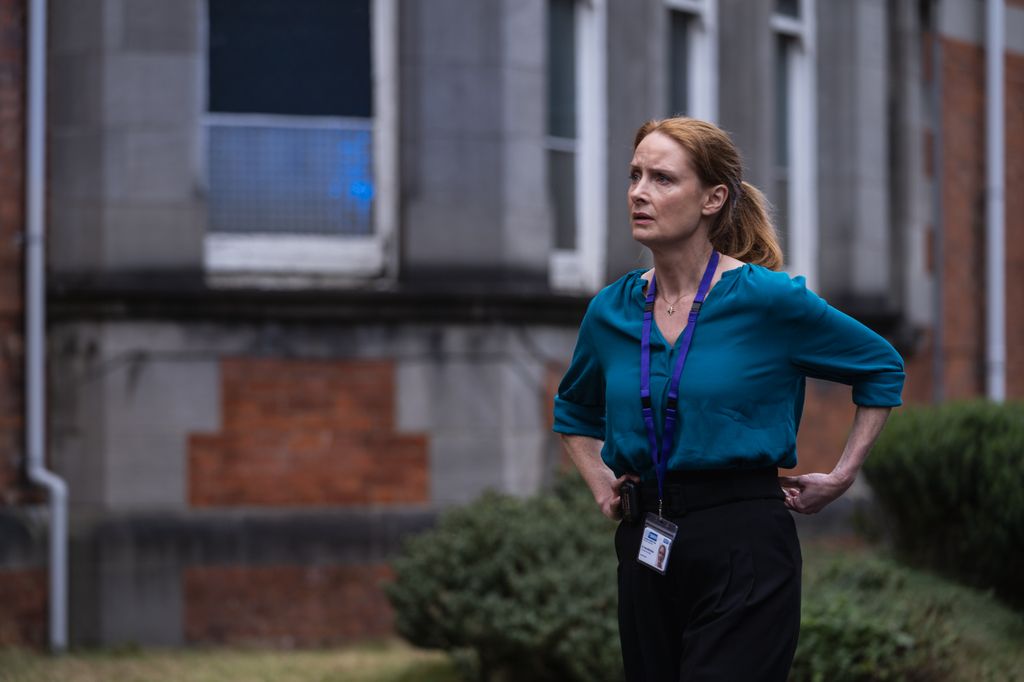 woman with red hair in blue shirt outside building