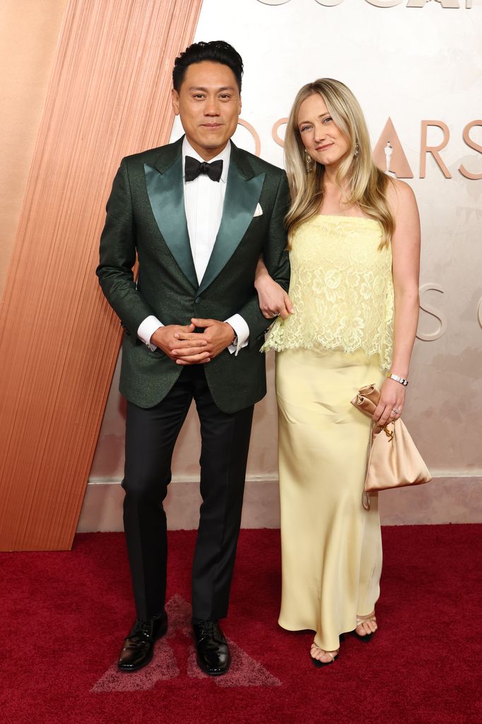 Jon M Chu and his wife Kristen Hodge link arms and pose for photographers while on the red carpet of the Oscars on Sunday 2 March 2025