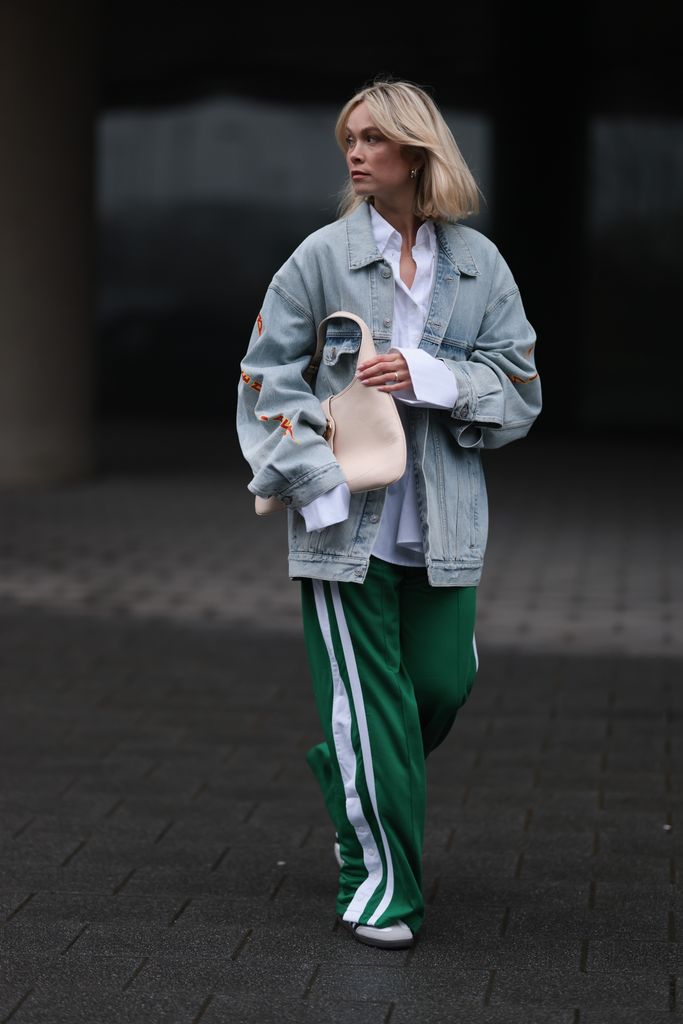 Nadine Berneis seen wearing Balenciaga light blue oversized logo denim / jeans jacket, Black Palms The Label white cotton oversized buttoned shirt, Karo Kaur Label green / white wide leg pants, Gucci beige / creamy white leather bag and Adidas Sambas