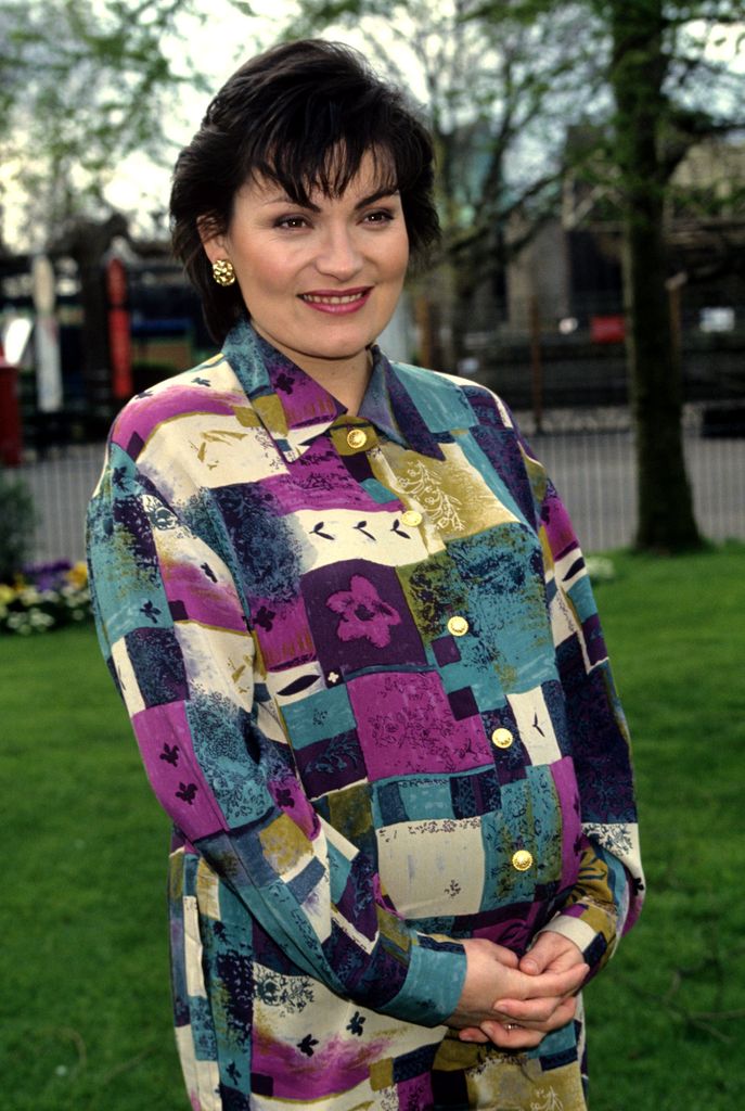 Lorraine Kelly cradling her baby bump in a patchwork dress