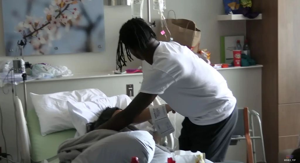 travis hunter leaning over wife in hospital bed