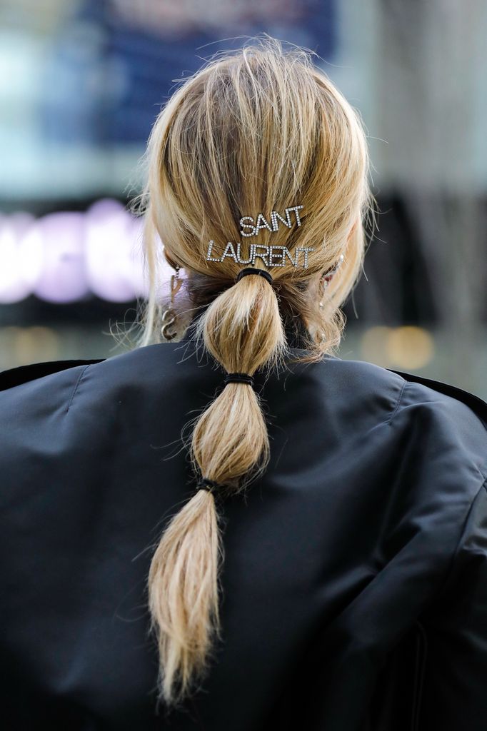 Influencer Gitta Banko wearing a low bubble ponytail hairstyle, a black bomber jacket by Saint Laurent, silver crystal heart 'YSL' earrings by Saint Laurent and silver crystal hair clips by Saint Laurent (all by Breuninger) 