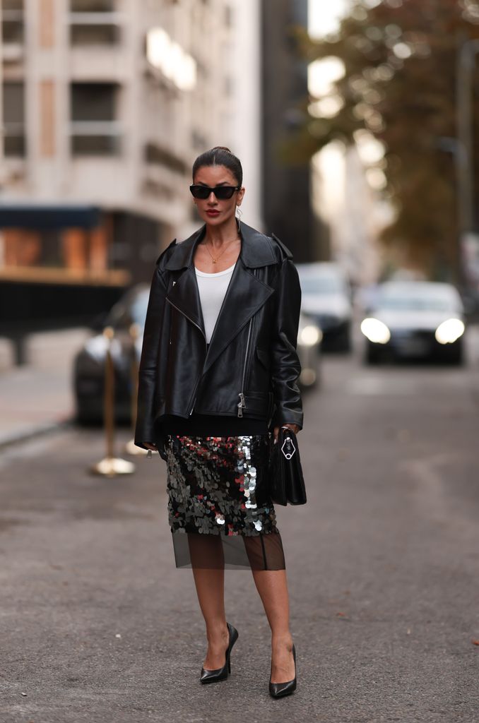 Lindner is seen wearing black sunglasses from Bottega Veneta, silver twisted earrings from Ole Lyngaard, a golden necklace, a black leather jacket from Dorothee Schuhmacher, underneath a white top from Dorothee Schuhmacher, a black knee-length skirt with silver sequins part from Dorothee Schuhmacher, a large black leather clutch from Louis Vuitton and pointed black leather heels from Balenciaga on September 26, 2023 in Paris 