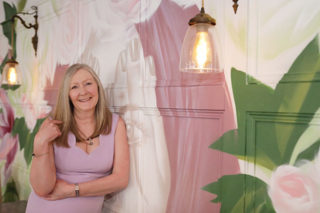 Woman in a lilac top against a floral background