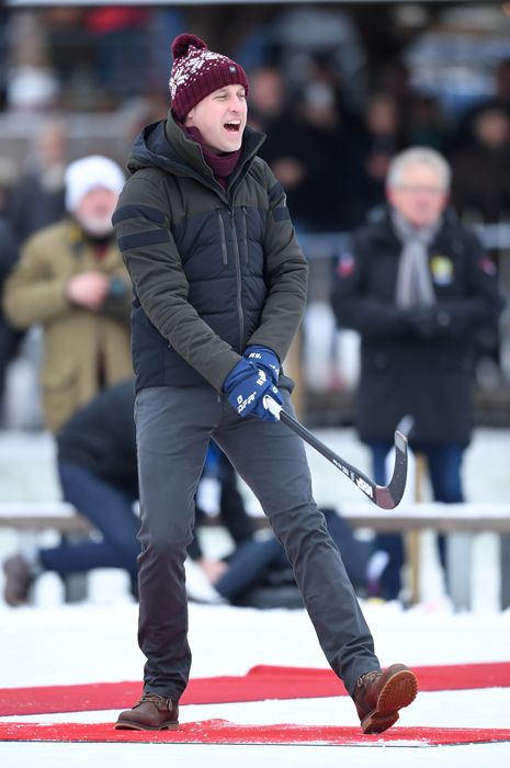 Prince William in winter clothes and a beanie hat playing ice hockey in Sweden