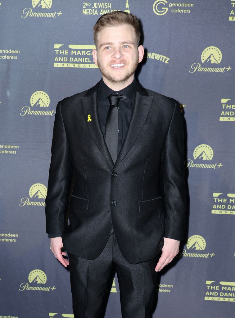 Jonathan Lipnicki smiling in a black suit