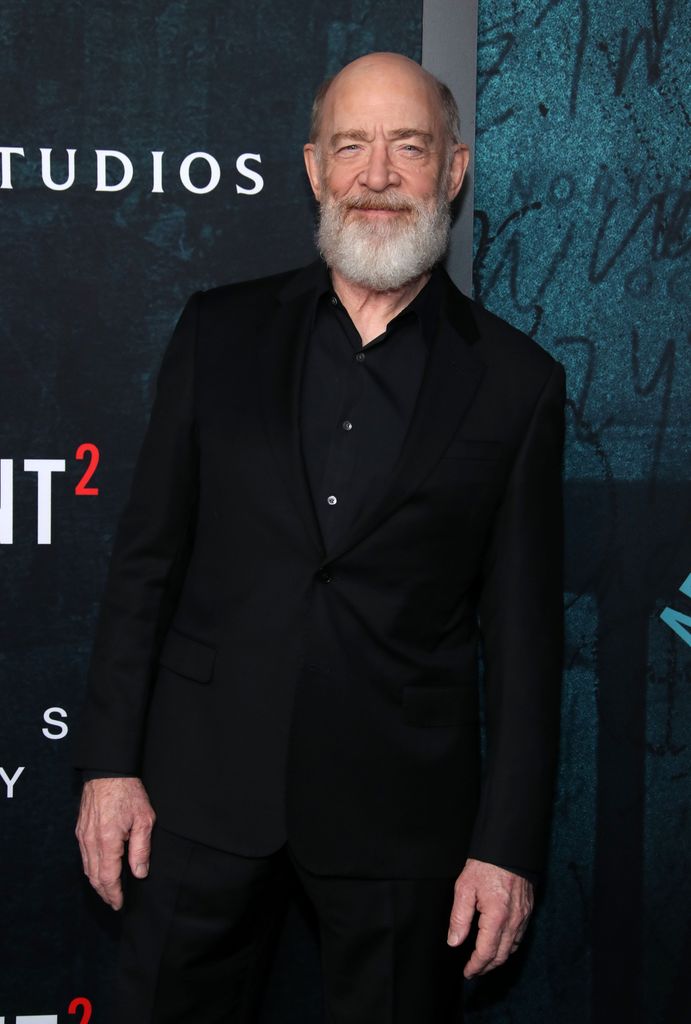 man in black suit posing for photo at photo call