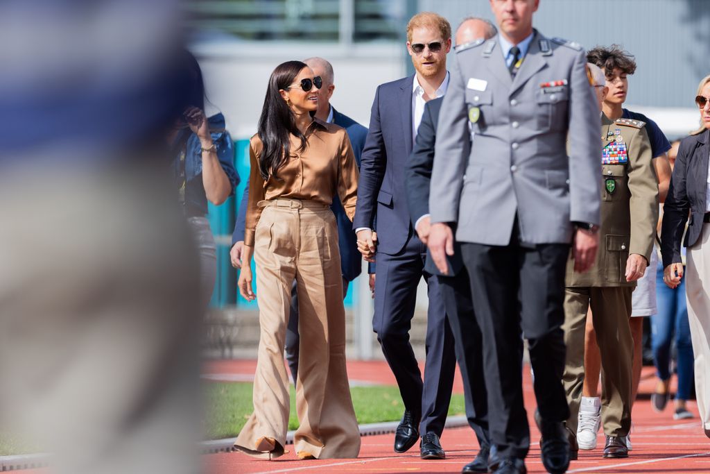 Prince Harry and Meghan walking on a track field together