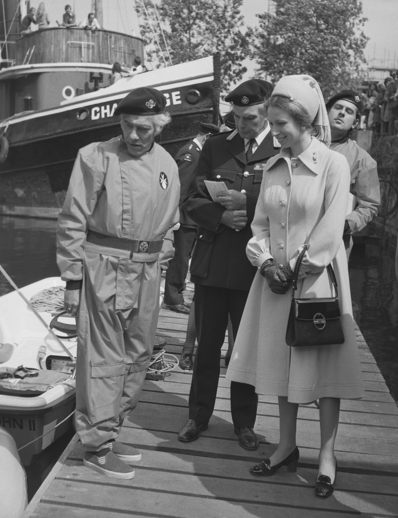 Princess Anne in a coat dress looking at a boat