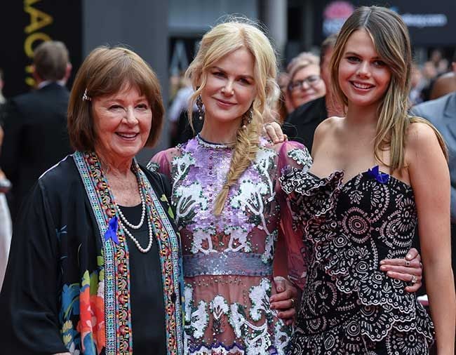 Nicole Kidman on a red carpet smiling with her arms around her mother, left, and niece, right