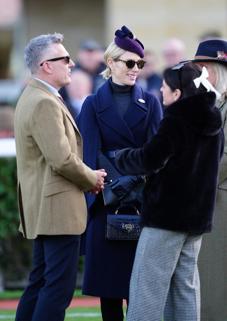 Zara talking to people in blue caped coat