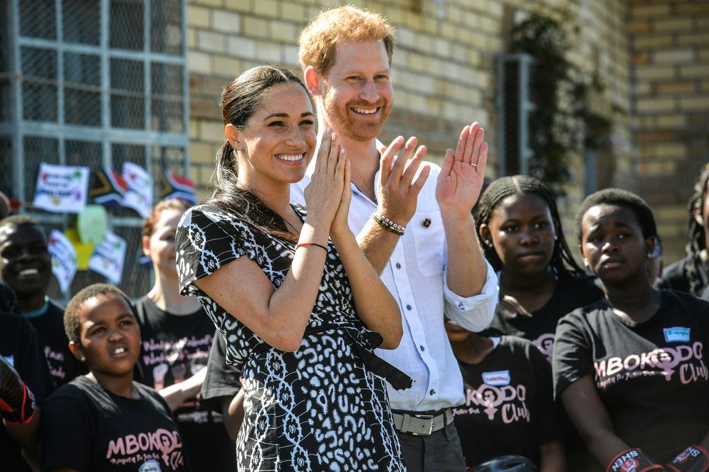 Prince Harry and Meghan laughing and clapping