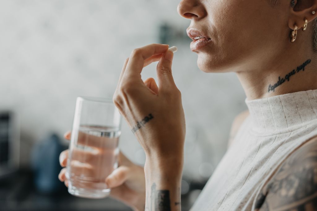 woman taking supplements with water 