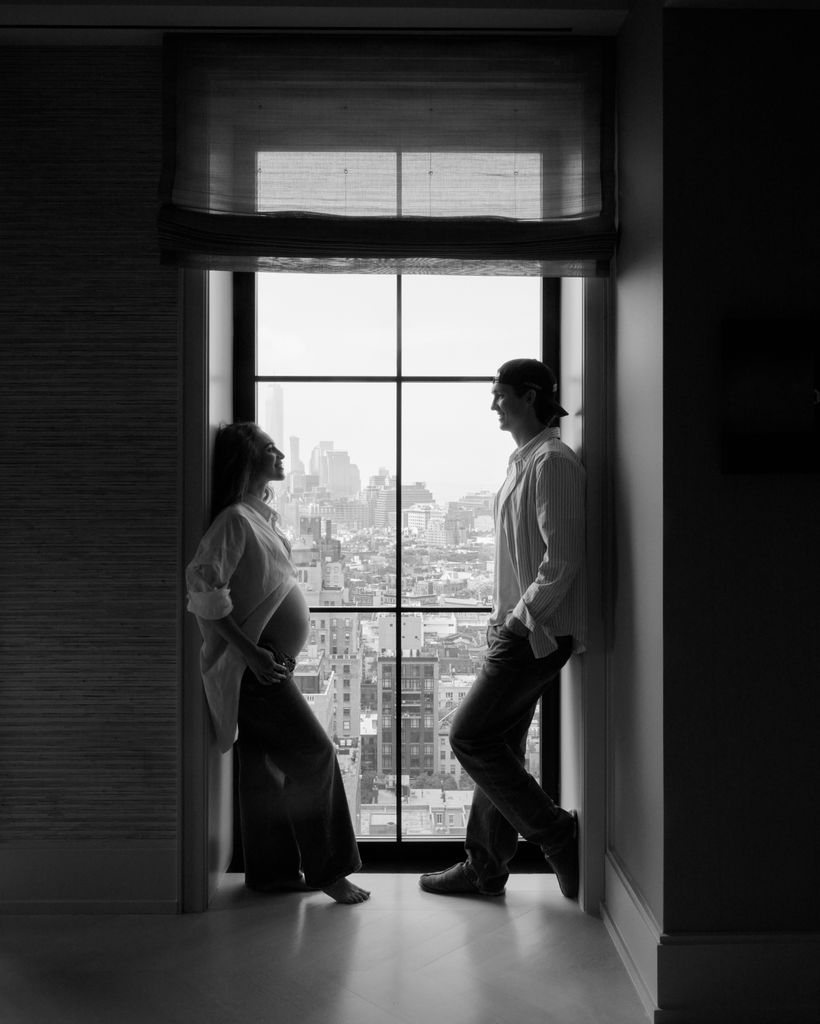 Black-and-white image of a pregnant Chloe Stroll opposite Scotty James overlooking a city