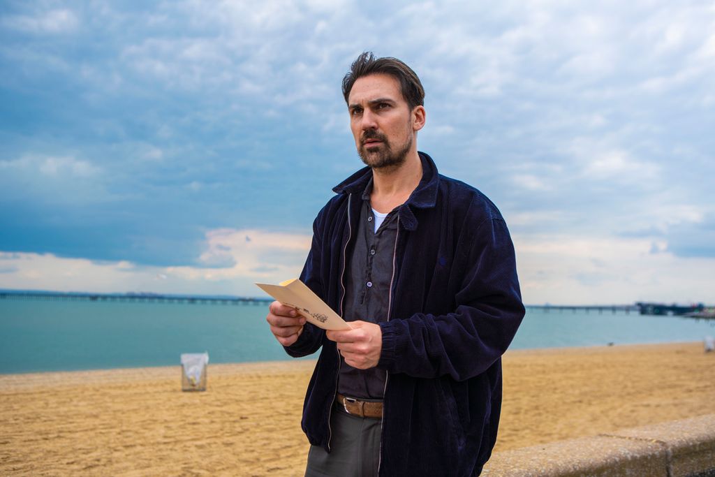 man holding paper standing next to beach