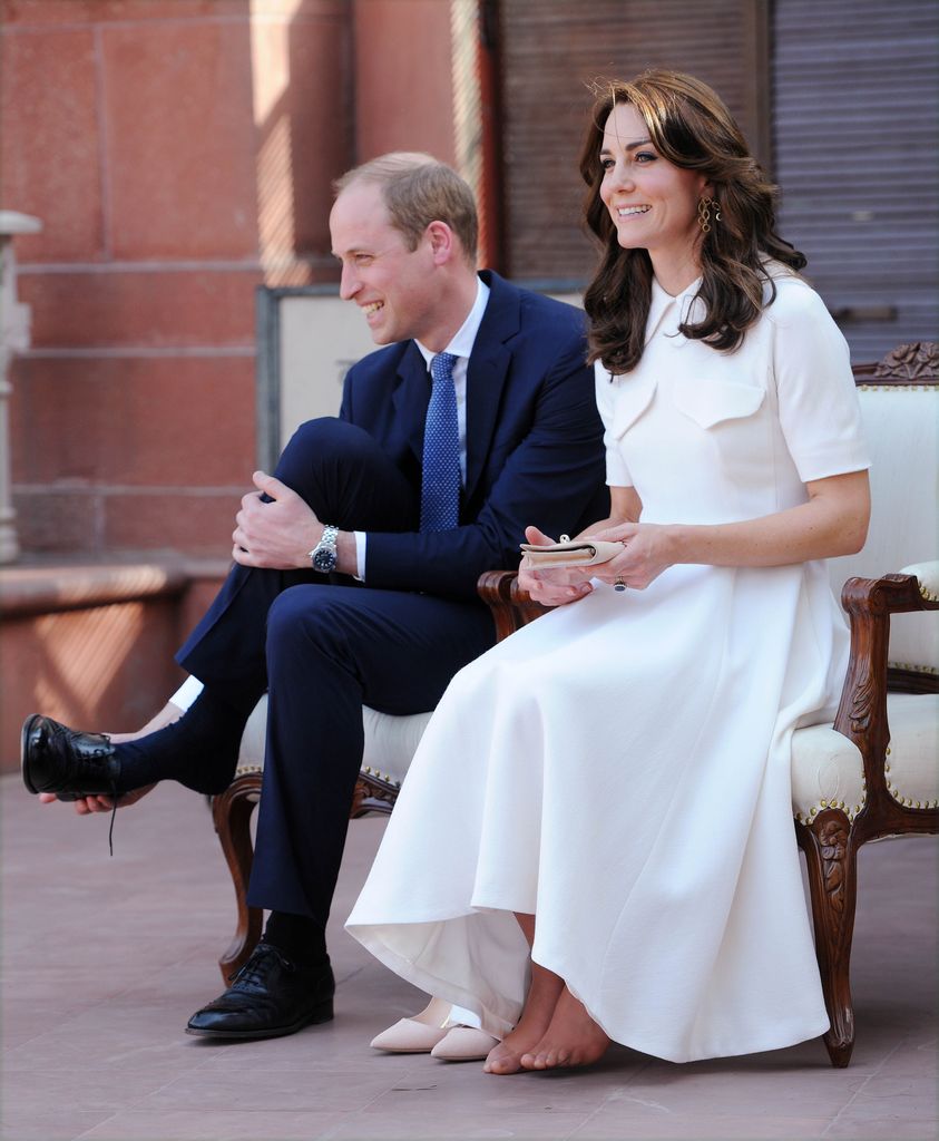 Princess Kate wearing a billowing white dress sitting next to Prince William 