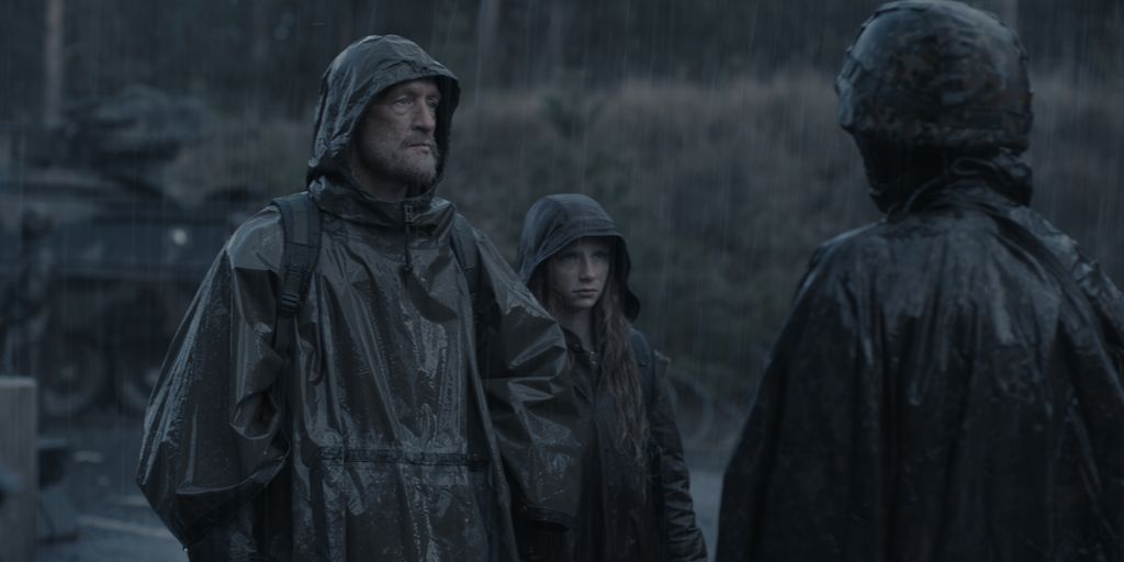 Two characters from Dark standing in the rain surrounding a military post