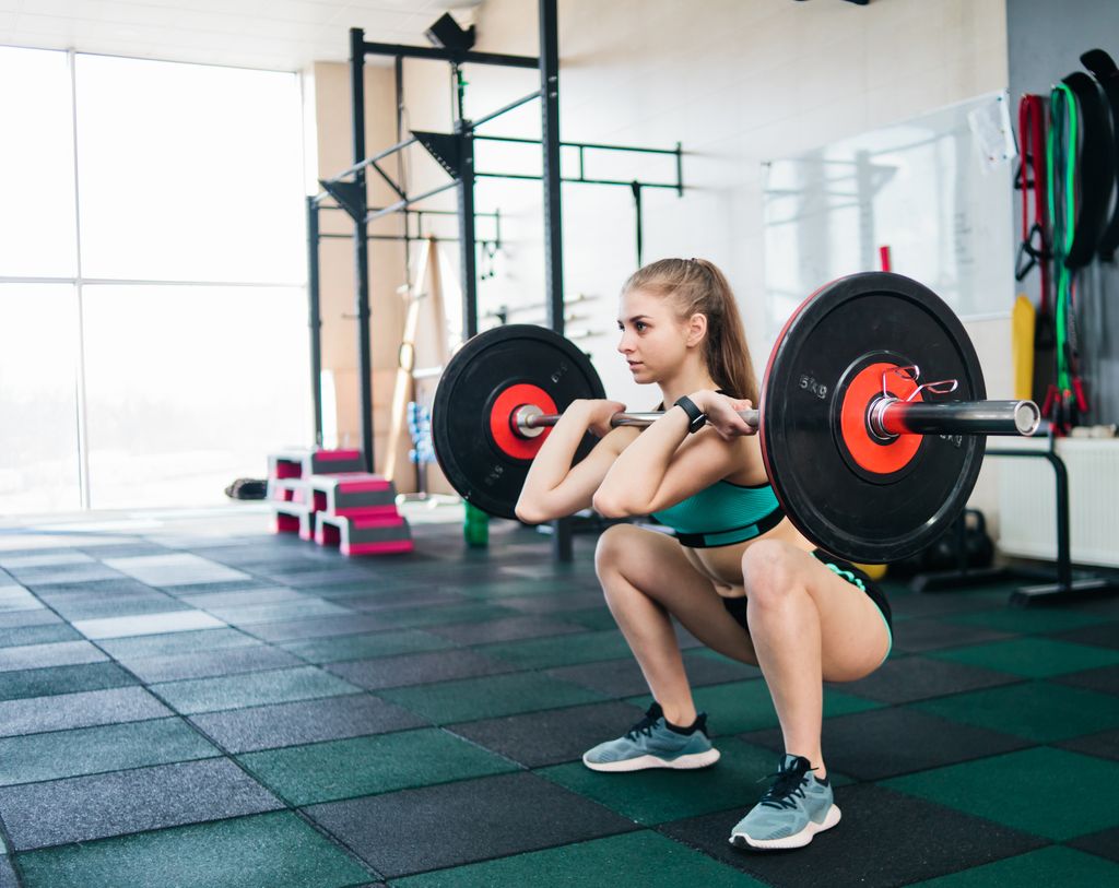 woman doing front squat with barbell in a gym