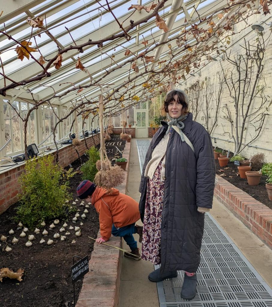 pregnant woman standing in a greenhouse with a small boy