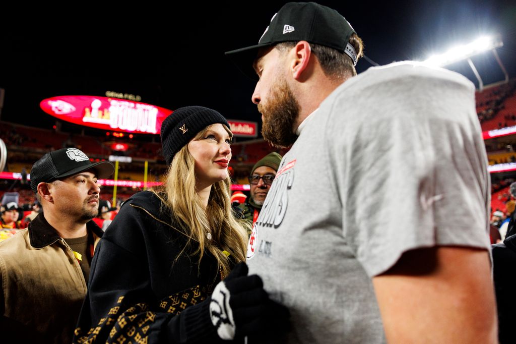 Taylor Swift's security stands watching as Travis Kelce #87 of the Kansas City Chiefs celebrates with Taylor on the field after the AFC Championship game