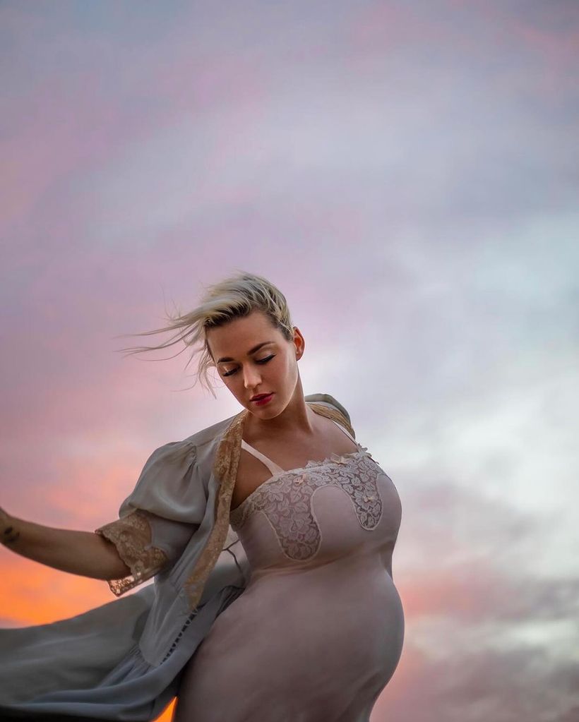 Pregnant Katy Perry against a dreamy sky wearing a silk dress