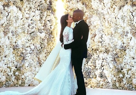 Kim in her white wedding dress kissing Kanye in his black tie suit