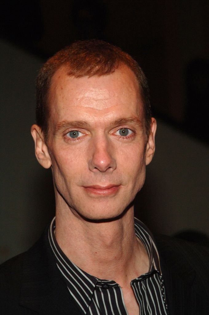 Doug Jones porte une chemise rayée noire et blanche avec un col ouvert.