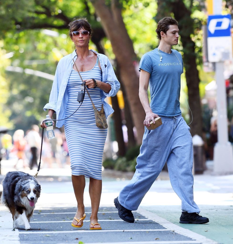 Helena Christensen in blue and white stripe dress walking dog with her son Mingus who wears blue t-shirt