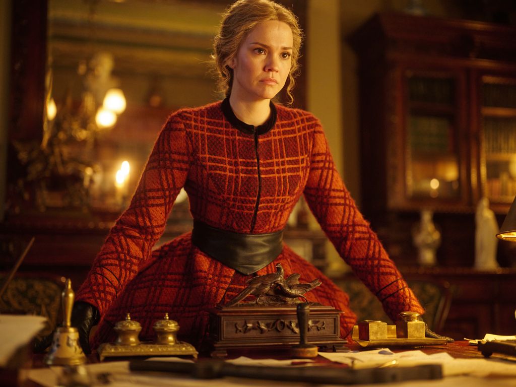 woman in period costume standing next to table 