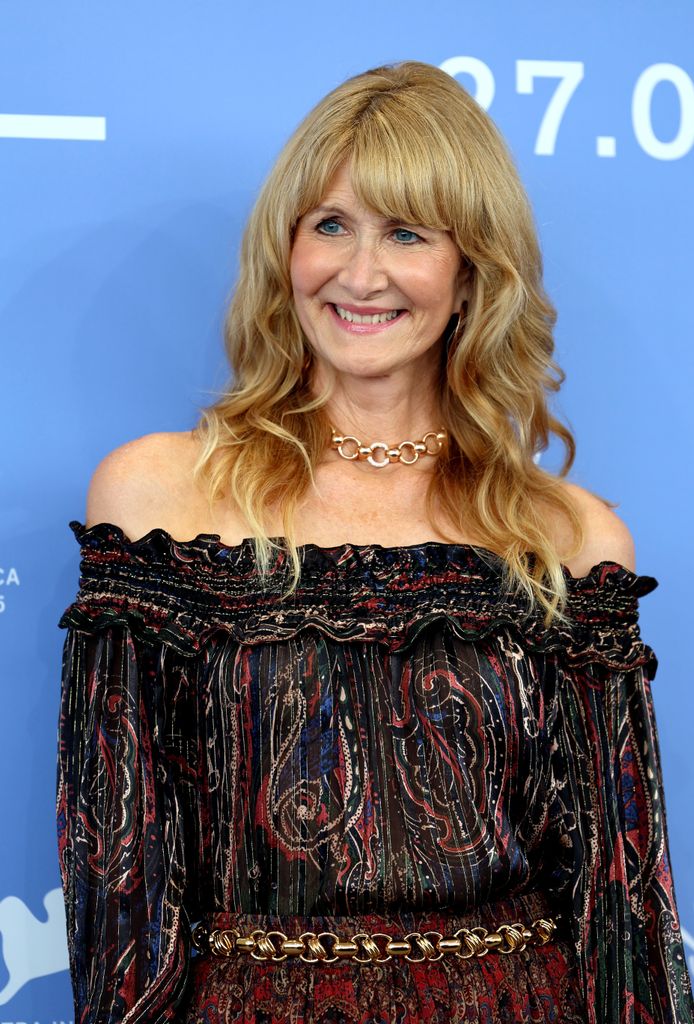 Laura Dern wears a boho esque off the shoulder dress with gold chain necklace and matching belt. 