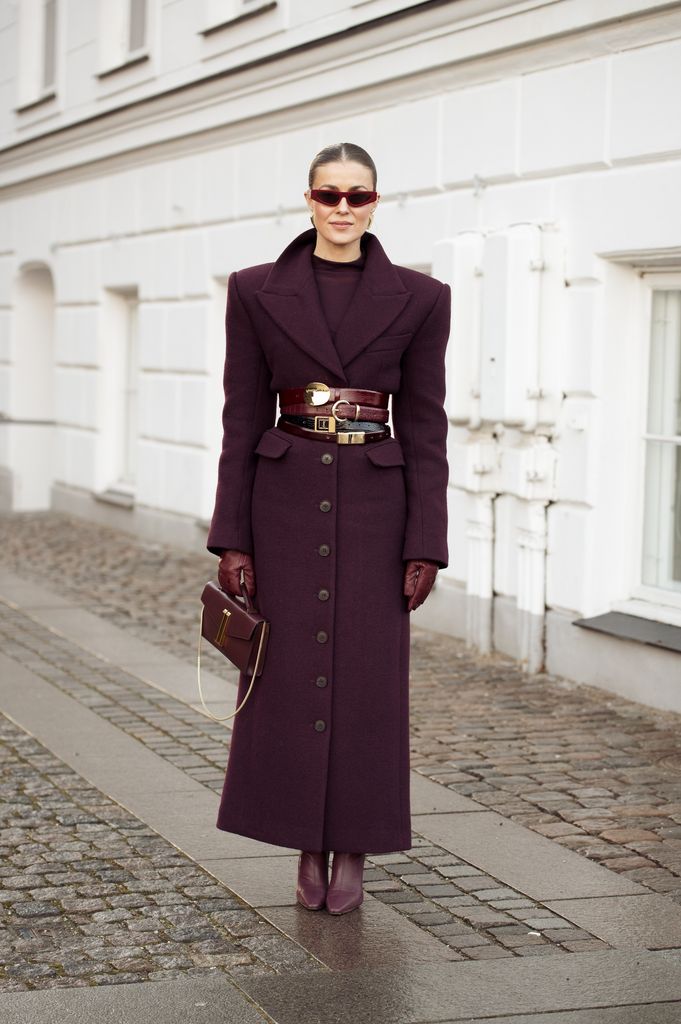 Nina Sandbech wears a burgundy top, long burgundy coat with multiple belts, burgundy bag, burgundy leather gloves and pointy burgundy shoes outside the Forza Collective show during the Copenhagen Fashion Week Autumn/Winter 2025 on January 27, 2025 in Copenhagen, Denmark.