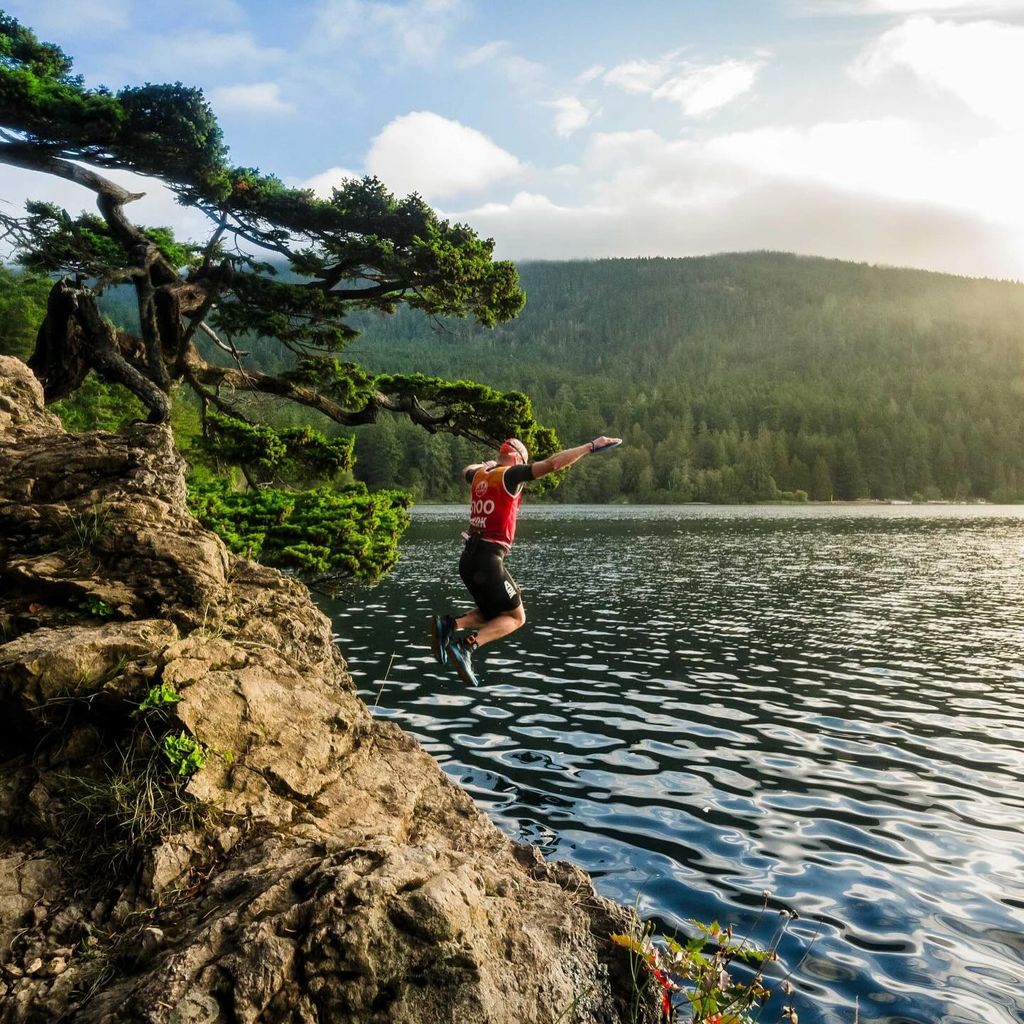 man jumping off cliff into lake