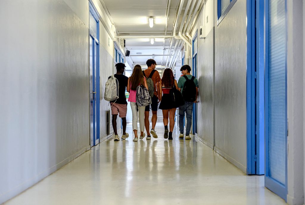 Rear view of a group of students walking in school corridor