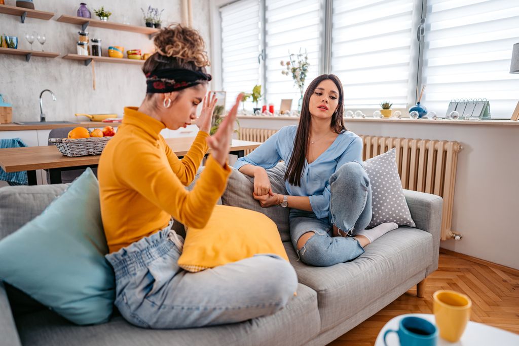 Two angry young women arguing at home during the day.