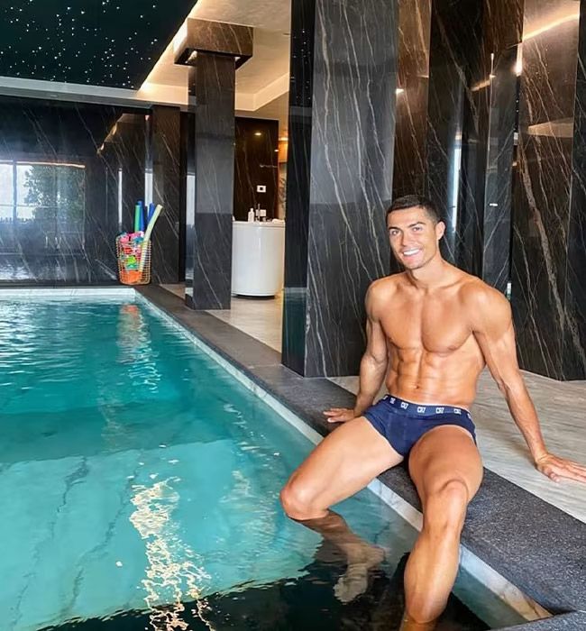cristiano ronaldo sat by indoor pool wearing swimming trunks