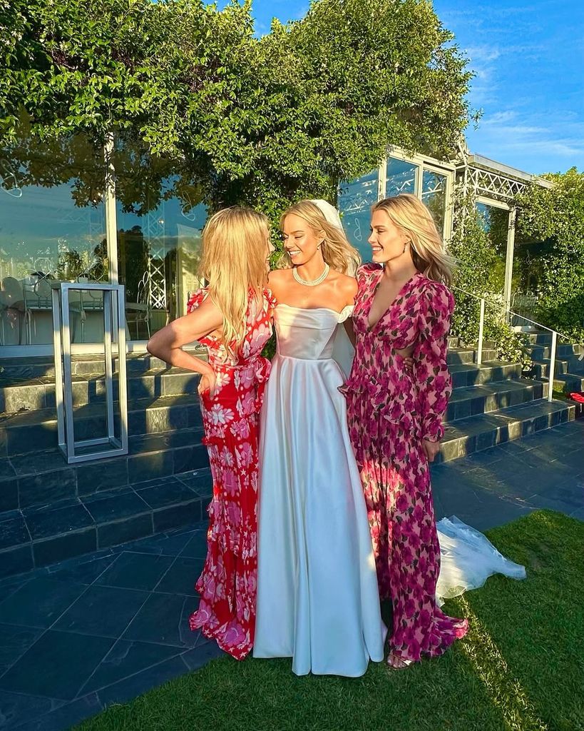 Lady Amelia and Lady Eliza Spencer in floral dresses either side of a bride