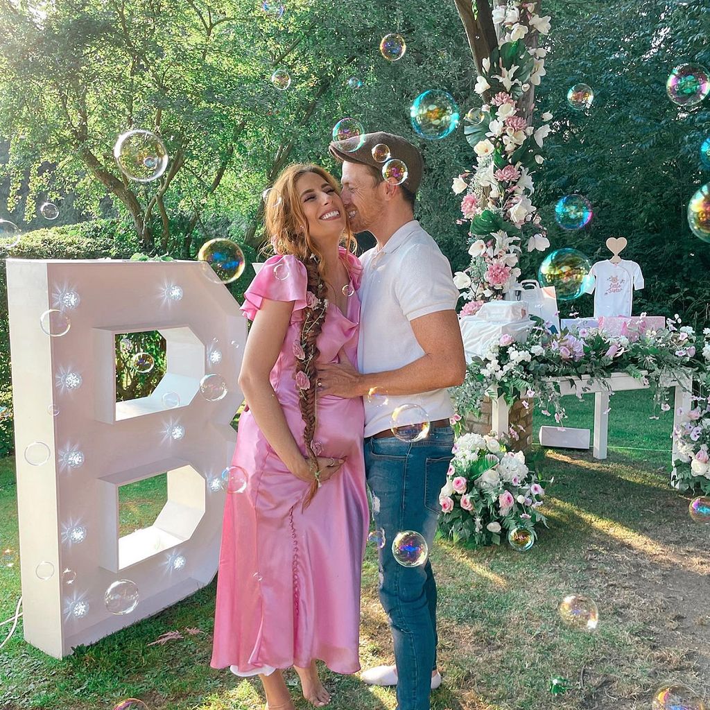 Stacey Solomon wears pink dress and holds her baby bump while Joe Swash kisses her cheek