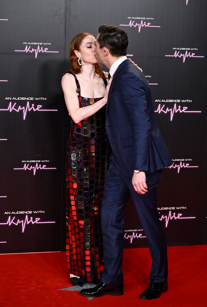 O casal se beijando no tapete vermelho