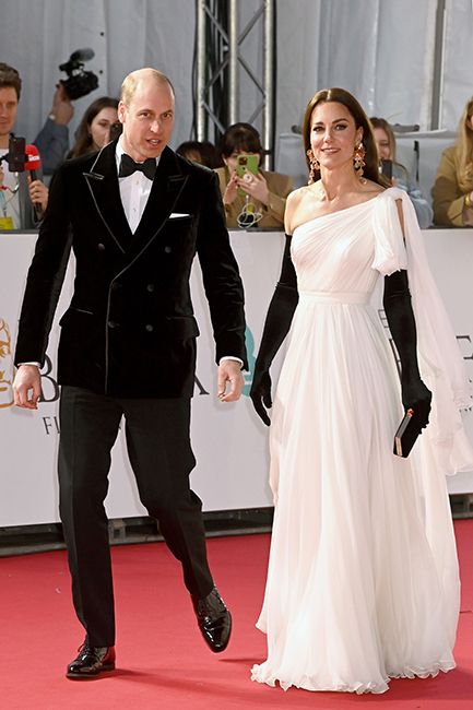 kate middleton in white bridal dress with black gloves walking bafta red carpet with william