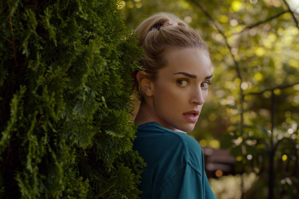 blonde woman hiding behind bush