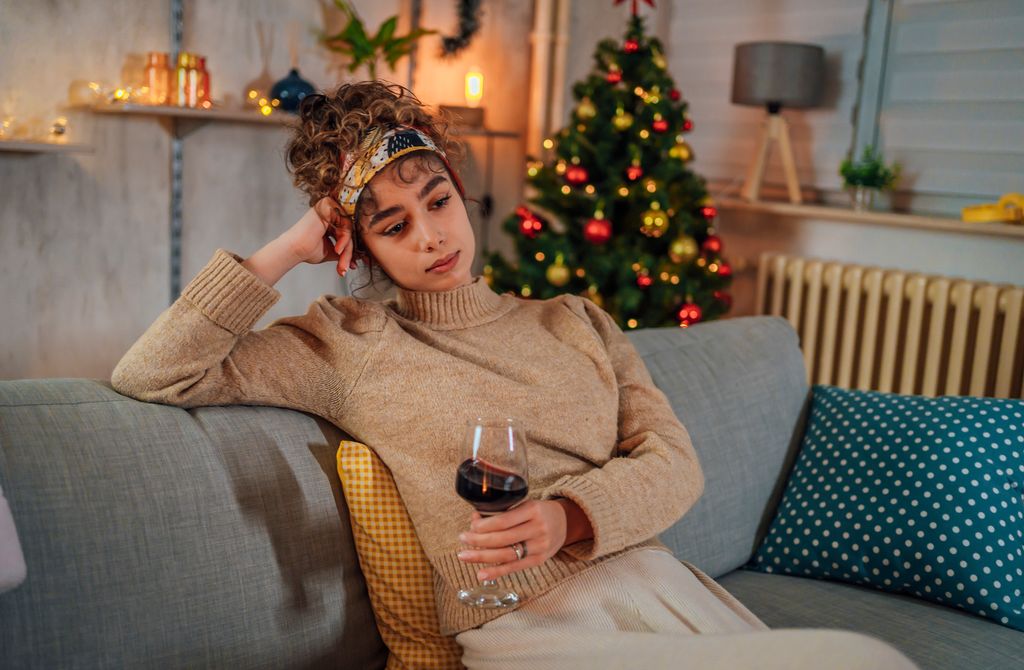 Young lonely woman drinking red wine during Christmas holiday