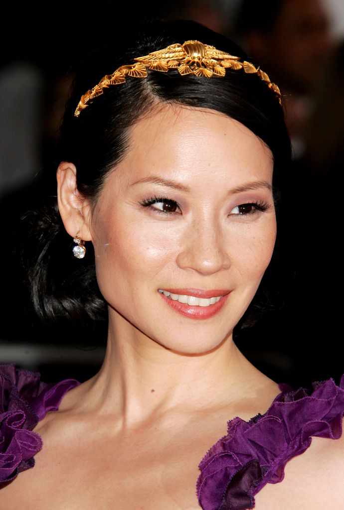 Lucy Liu at the 2007 Met Gala wearing a gold laurel headpiece and a purple gown with floral shoulder details.