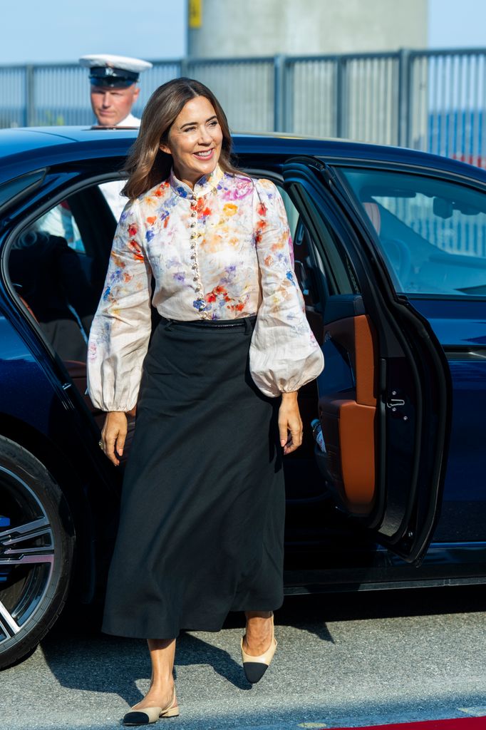 Queen Mary of Denmark arrives at Ocean Kaj wearing a floral long sleeve shirt, a long black skirt, and black and pink flat shoes