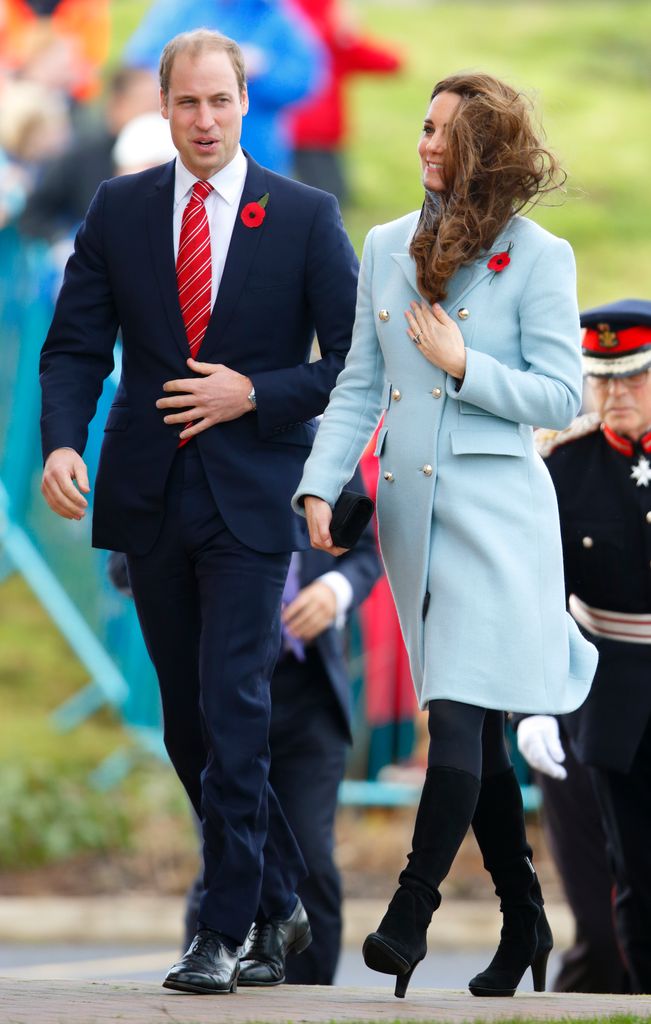 Kate in blue coat with windswept hair beside william