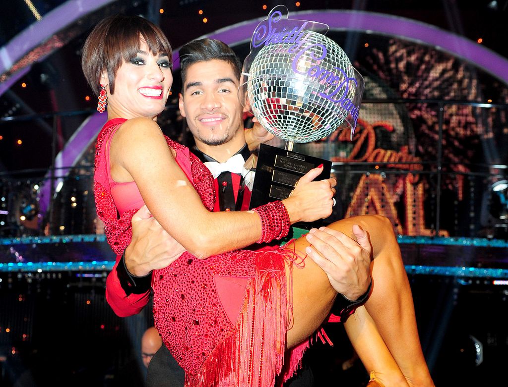 Louis Smith carrying Flavia Cacace and a trophy