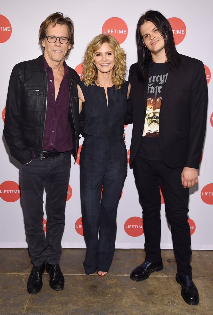 Kyra Sedgwick, Kevin Bacon and their son Travis Bacon smiling on a red carpet