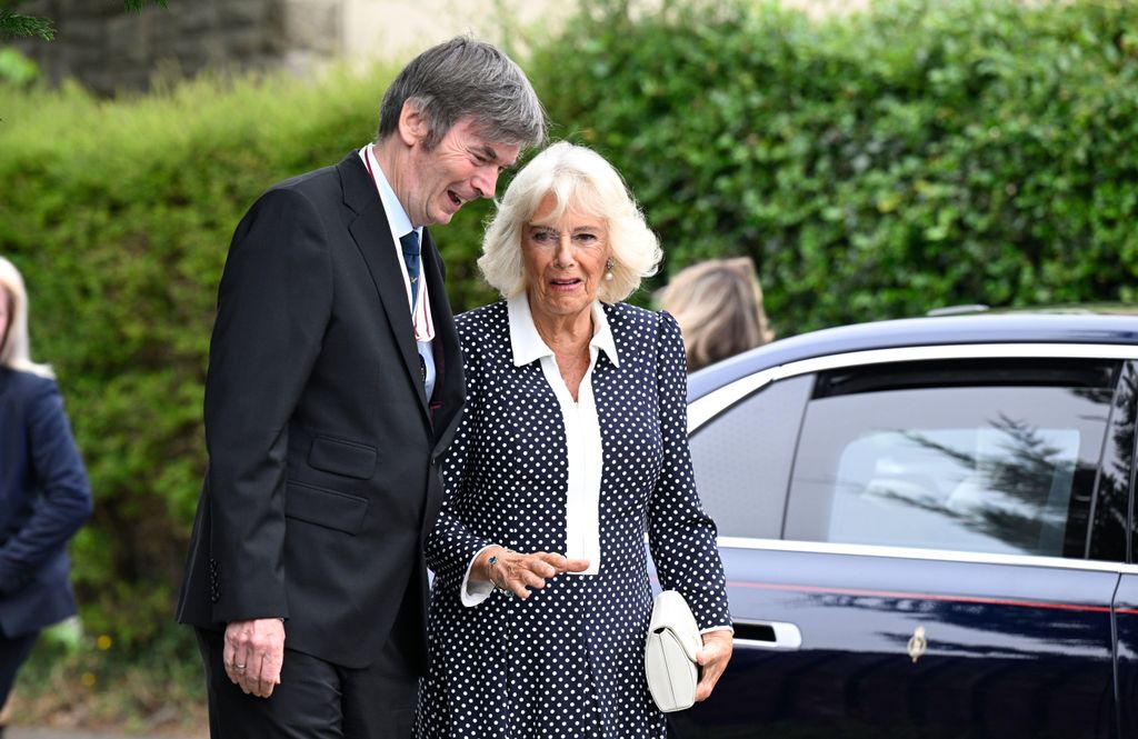 queen camilla walking next to man in polka dot dress