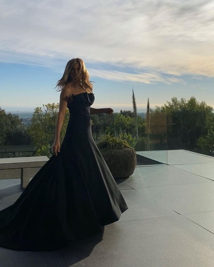 Jennifer Aniston in a strapless black dress on her balcony