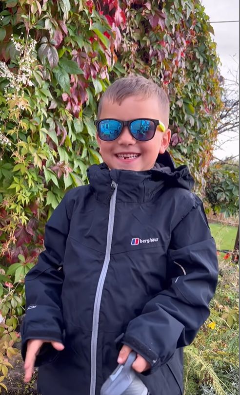 A child in a waterproof coat and sunglasses